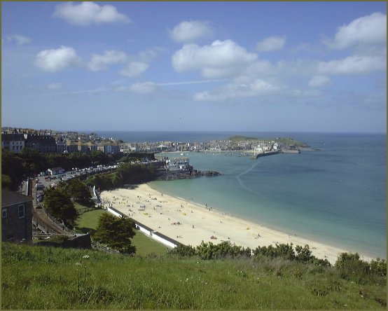 A classical sandy beach in a bay, viewed from the hill above