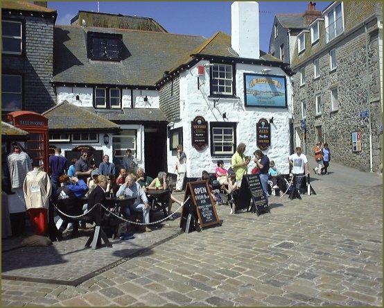 An old inn (whitewashed stone walls) with forecourt busy with customers